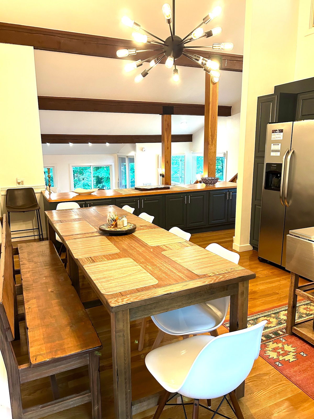 A modern white kitchen with a large farmhouse dining table and stylish seating.