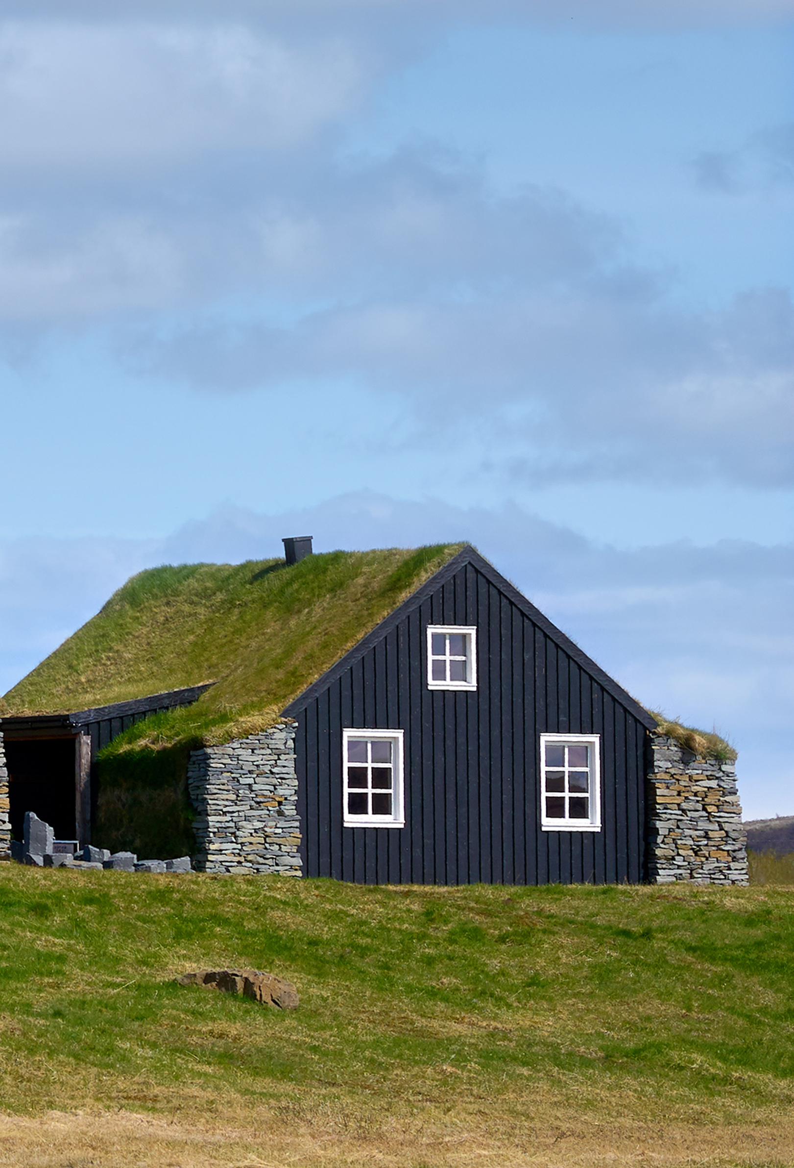 Traditional Icelandic turf houses with green grass roofs and dark wood siding at Torfhús Retreat.
