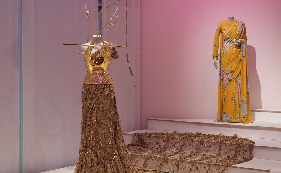 A collection of contemporary and experimental saris displayed in a museum setting.