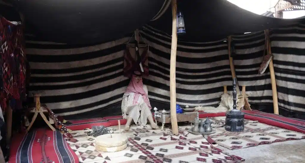 Interior of a traditional Bedouin goat-hair tent with carpets and brass coffee pots.