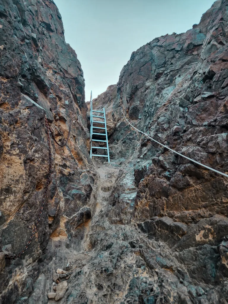 A lone backpacker walking through a deep, dramatic canyon in Oman.