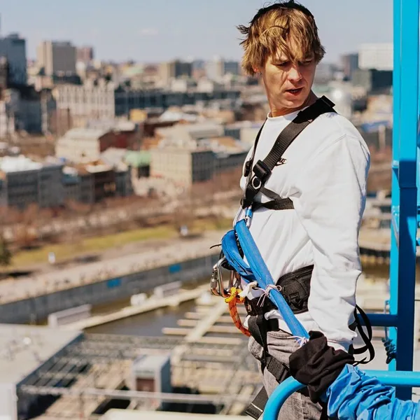 A person bungee jumping with the historic skyline and water of Montreal's Old Port in the background.