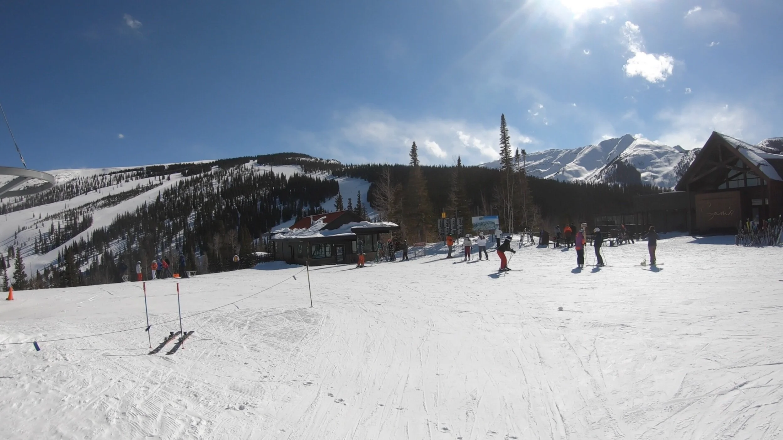 A wide-angle view of expansive alpine ski terrain under a clear blue sky.