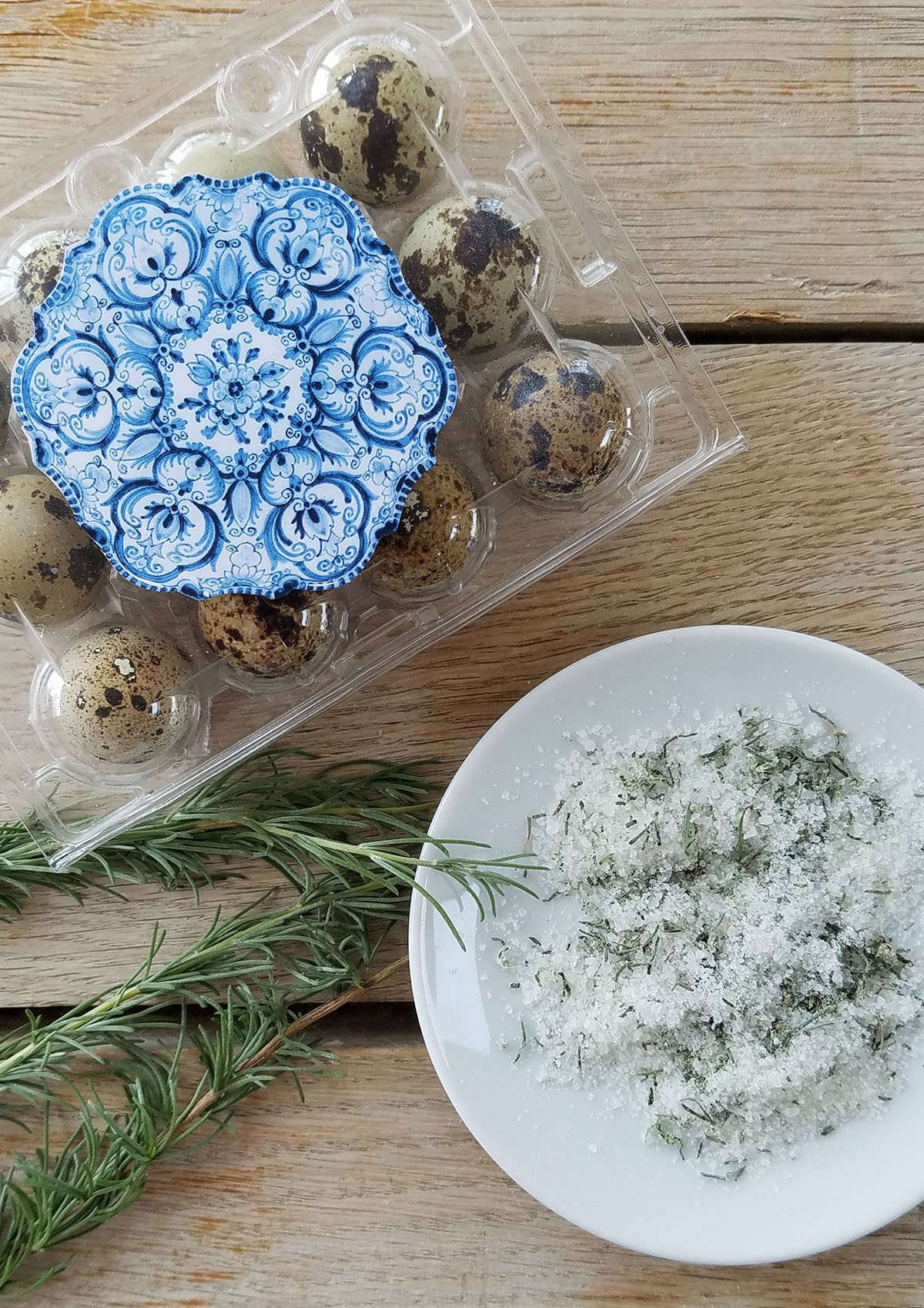 Peeled quail eggs served on a bed of wild herbs with a side of green rosemary salt.