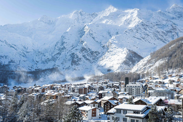 A sunny day view overlooking the rooftops of Saas-Fee village with mountains in the background.