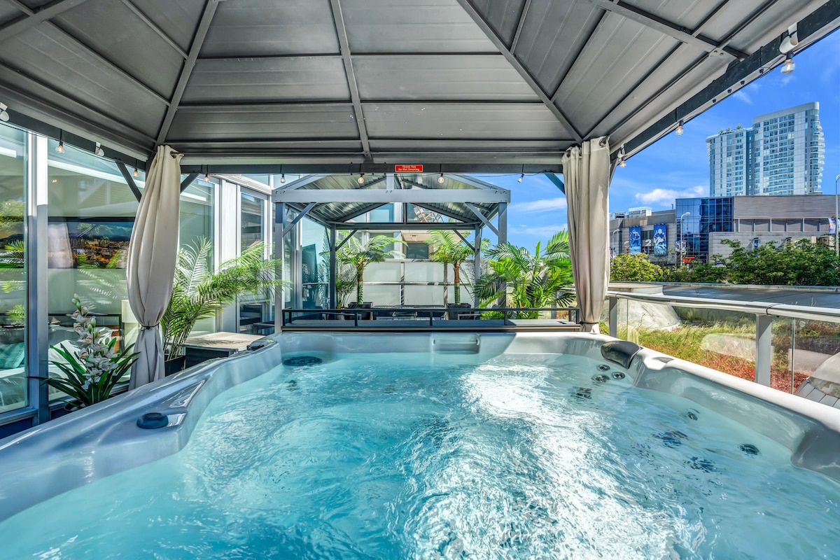 A private hot tub under a wooden gazebo with a view of the Vancouver skyline.