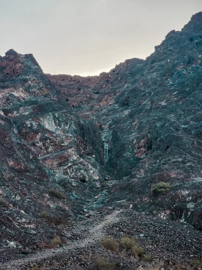 A hiker traversing a narrow trail along a high, rugged mountain ridge.