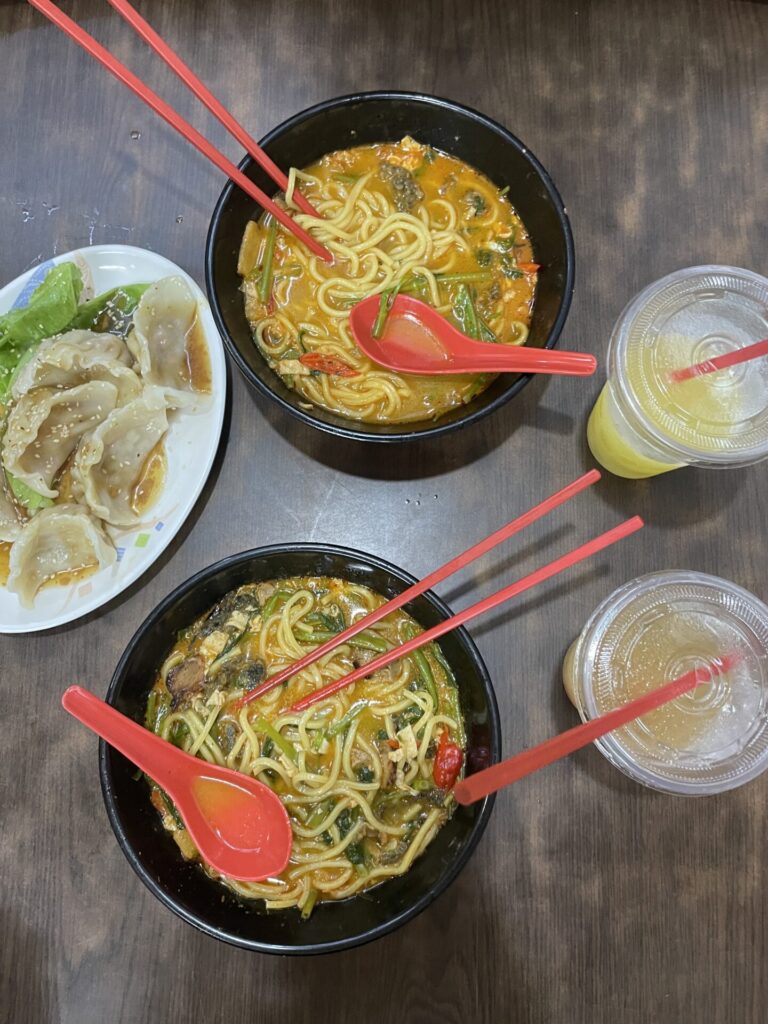 A cocktail glass on a table at a rooftop bar with the Marina Bay Sands towers in the background.