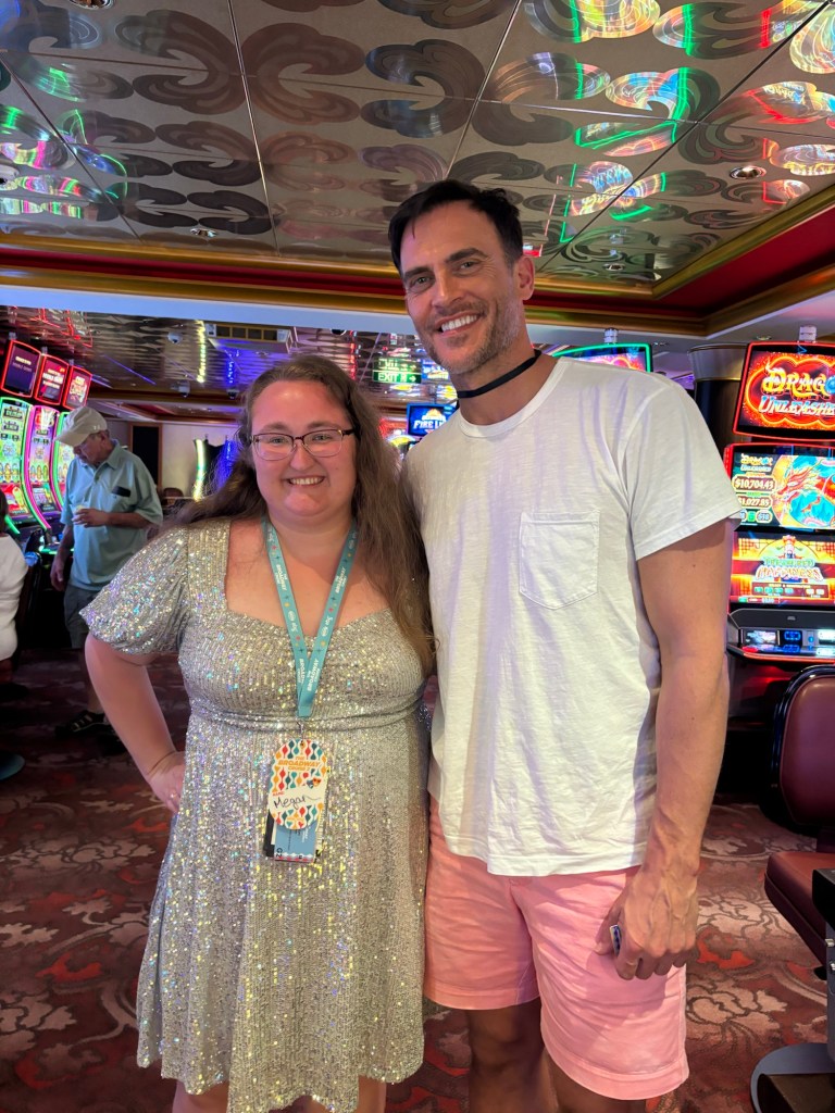 A smiling fan taking a photo with a famous Broadway actor on a cruise ship deck.