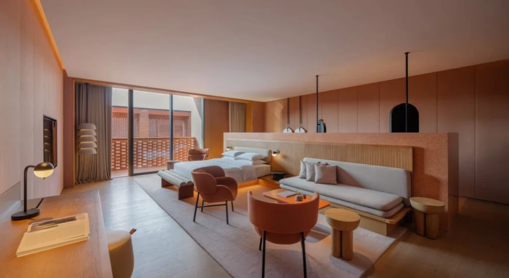 A bedroom interior featuring a warm neutral color palette and large floor-to-ceiling windows.