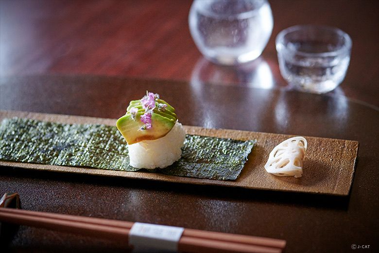 A close-up of meticulously prepared sushi pieces featuring vegetable toppings instead of fish.