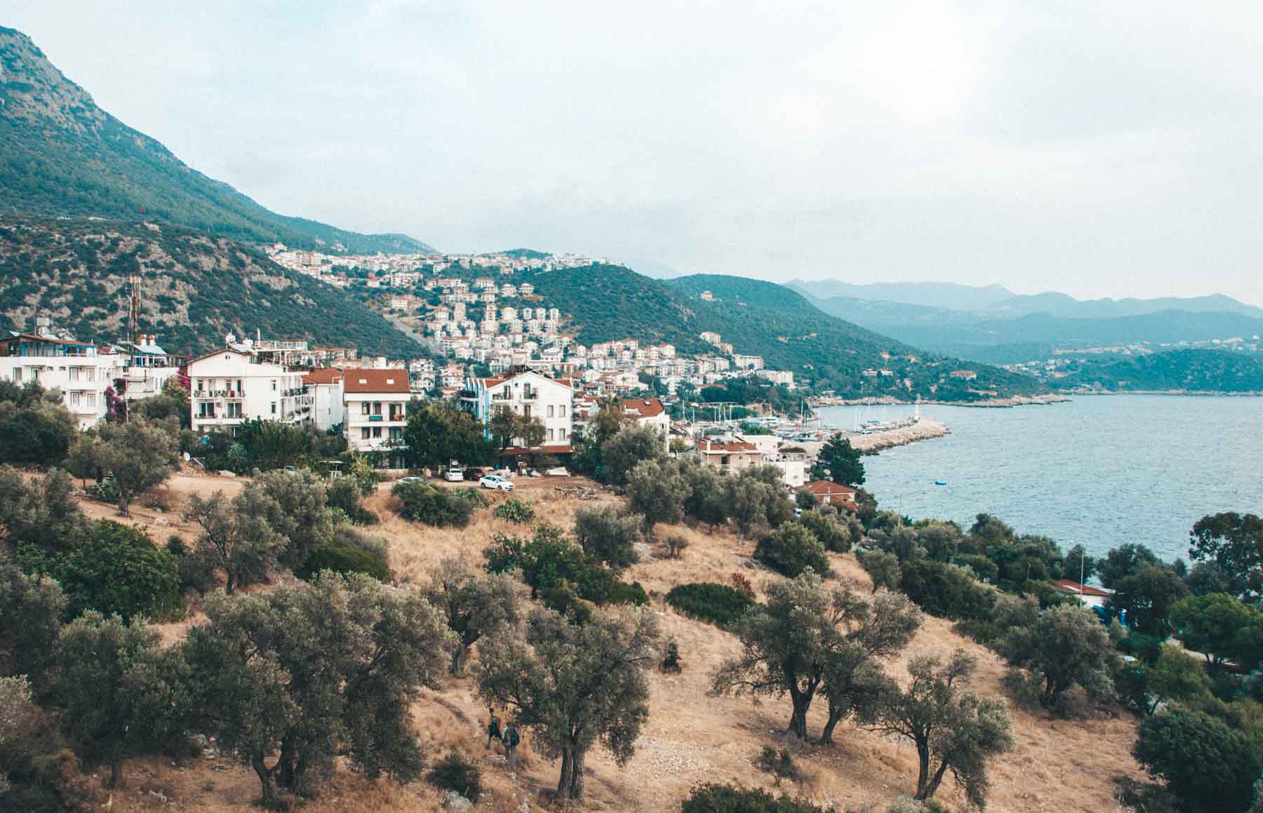 A narrow, colorful street in Kaş with traditional architecture and bougainvillea flowers.