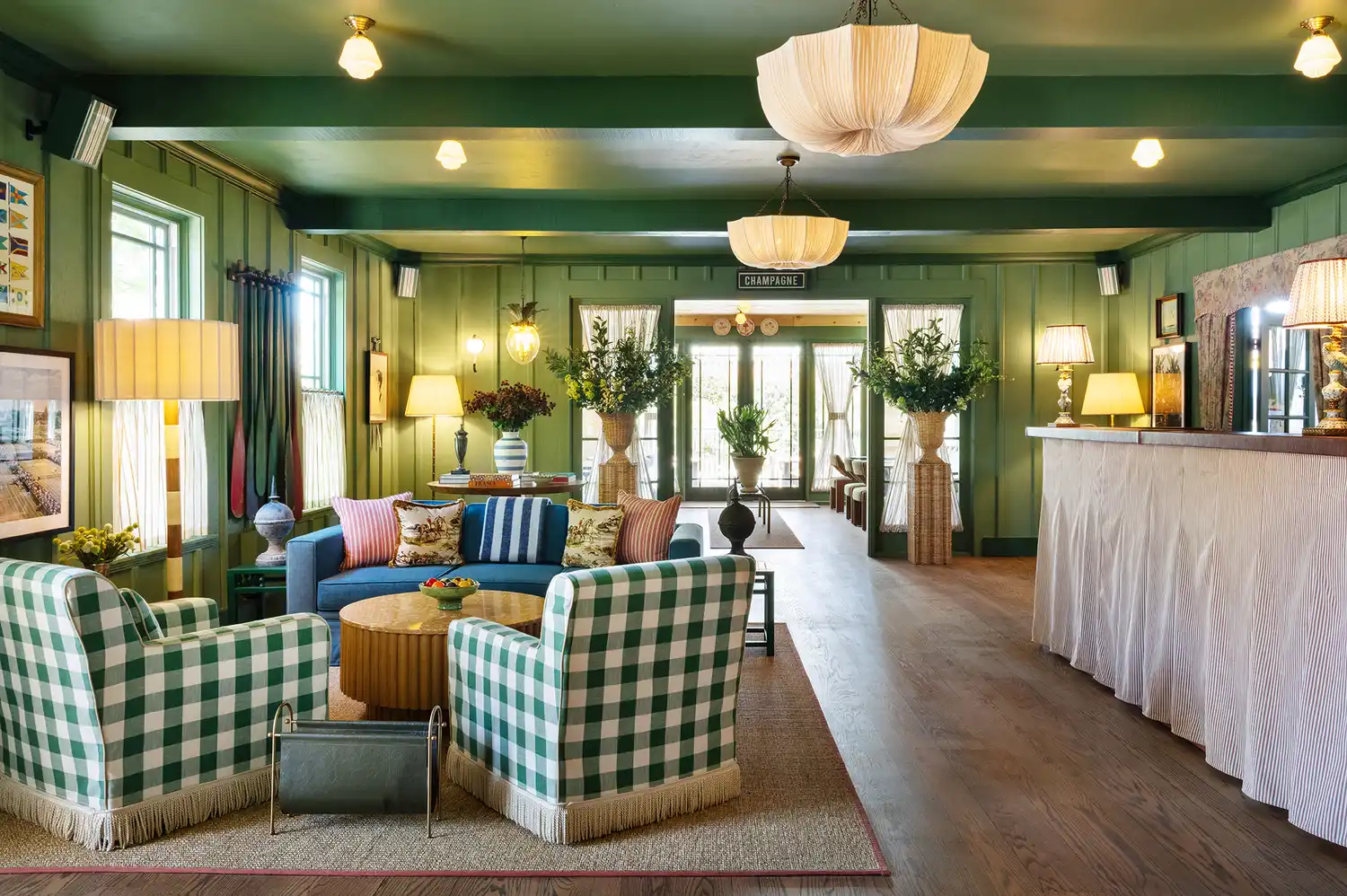 A warmly lit boutique hotel lounge with green-and-white patterned seating and a small bar.