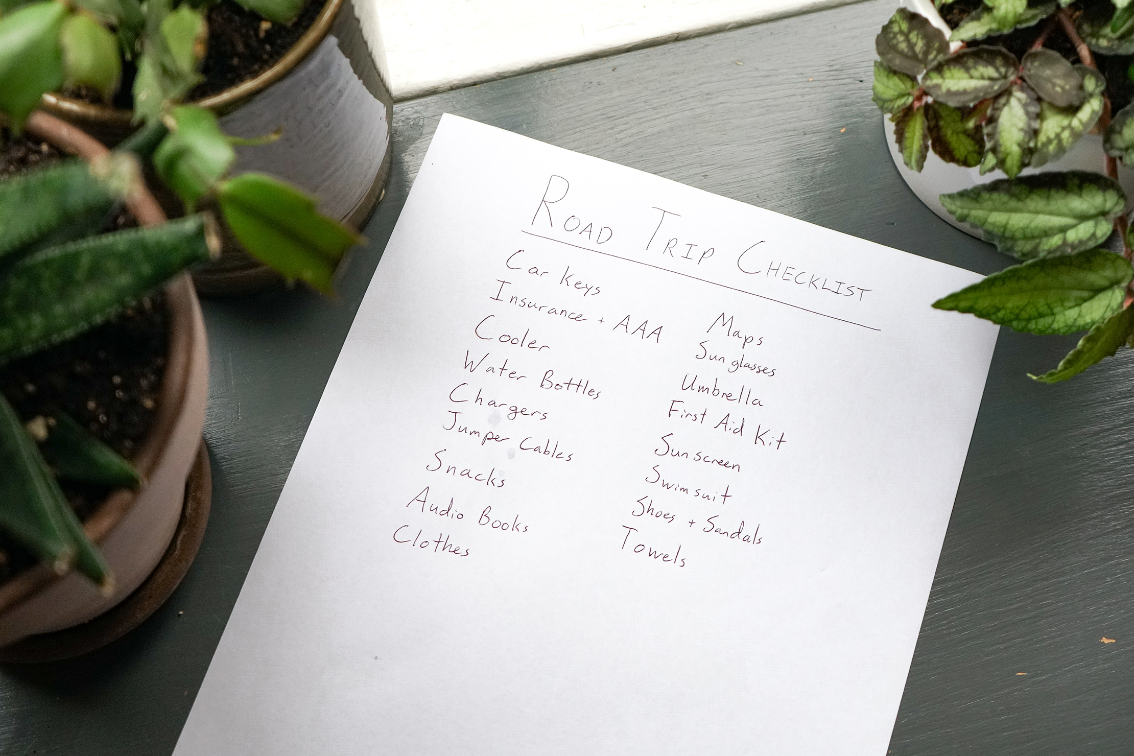 A handwritten road trip packing checklist on a piece of paper.