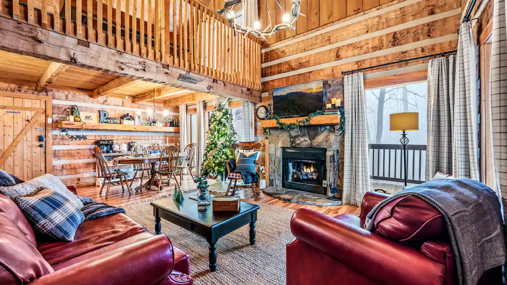 A traditional log cabin in Pigeon Forge, Tennessee, surrounded by snow and holiday lights.