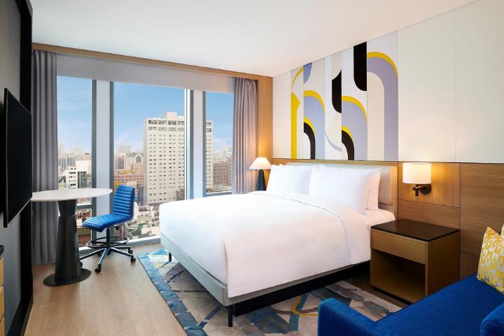 Indoor swimming pool with large windows overlooking the Seoul skyline at Le Méridien