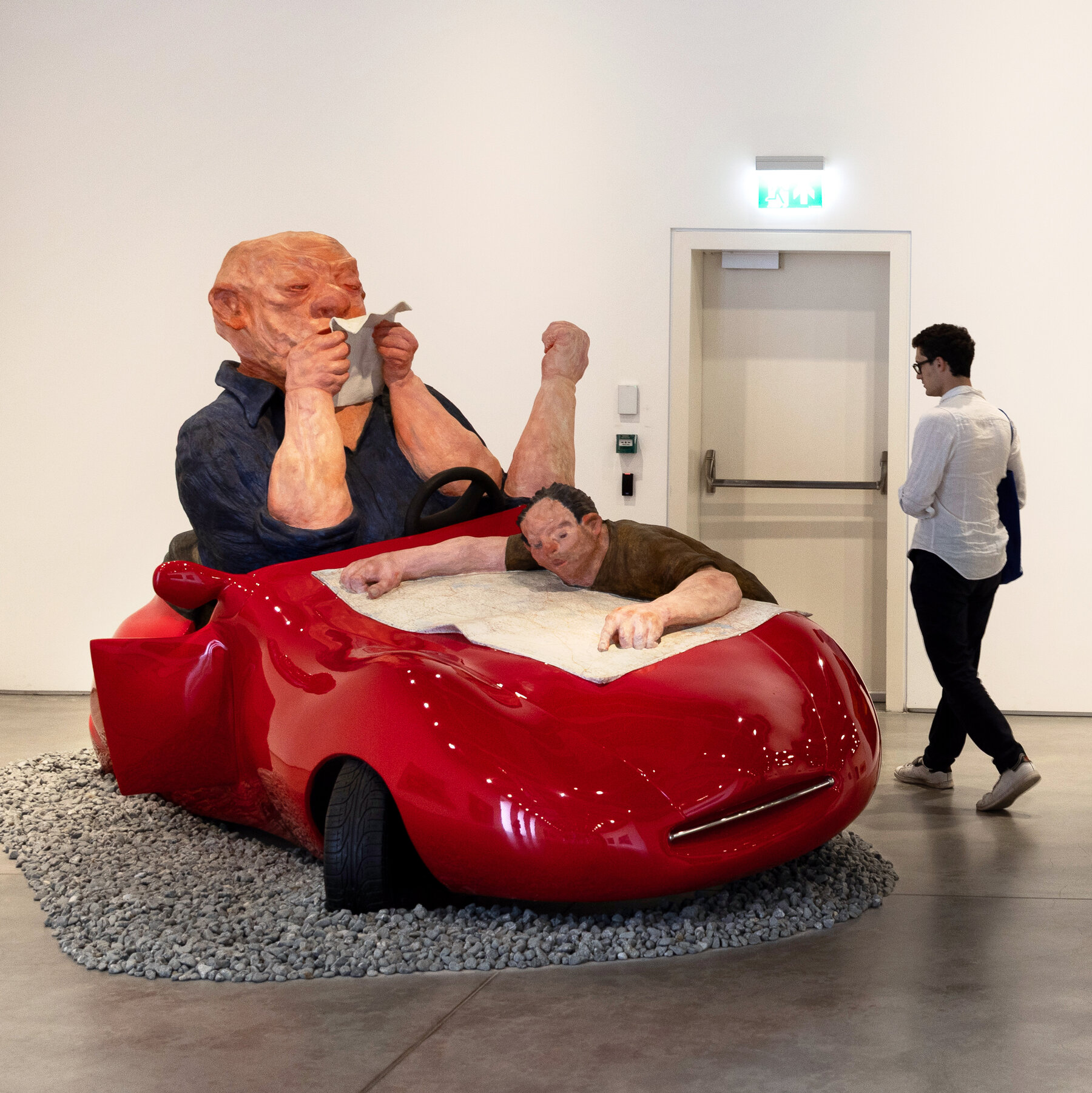A modern art sculpture of a man in a red car at the Istanbul Modern museum.