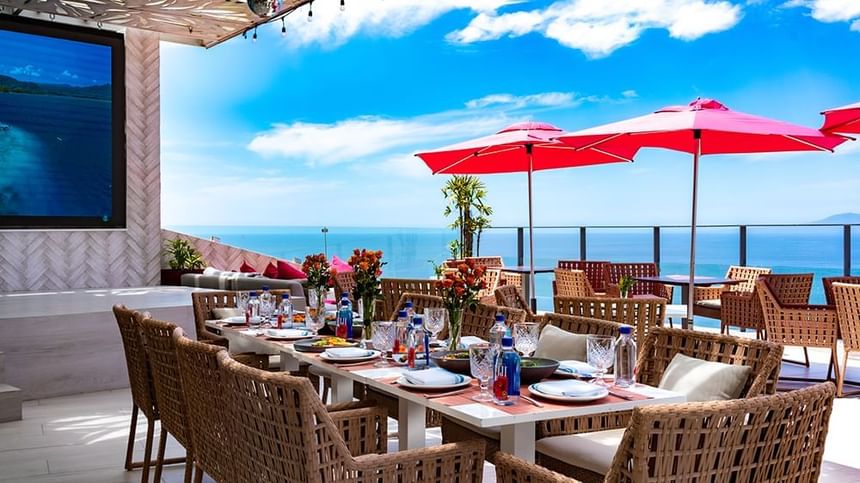 A wide view of The Top Sky Bar dining area overlooking the ocean and city coastline.
