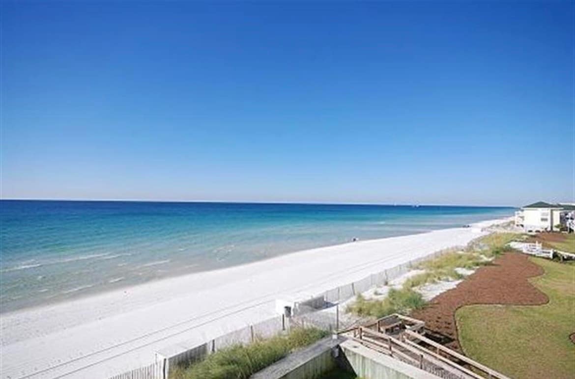 Direct eye-level view of a pristine white sand beach meeting clear emerald green ocean water.