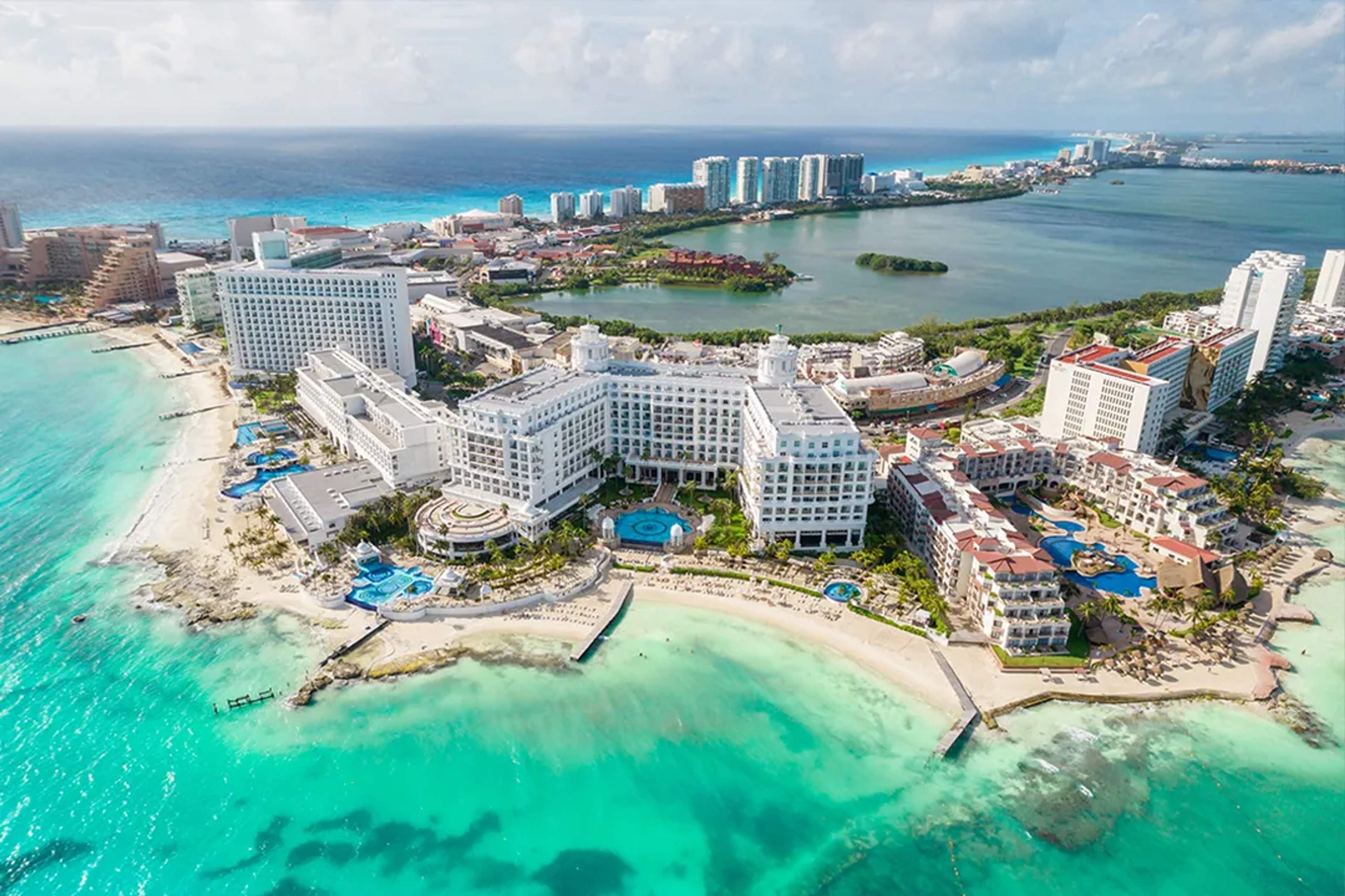Aerial perspective of premium beachfront hotels along a quiet stretch of white sand in Cancún.