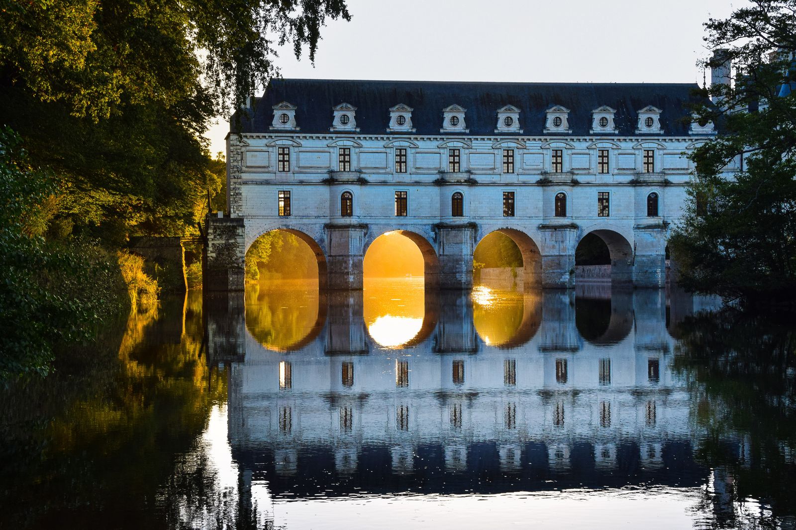 The historic Château de Chenonceau spanning across water in the French countryside.