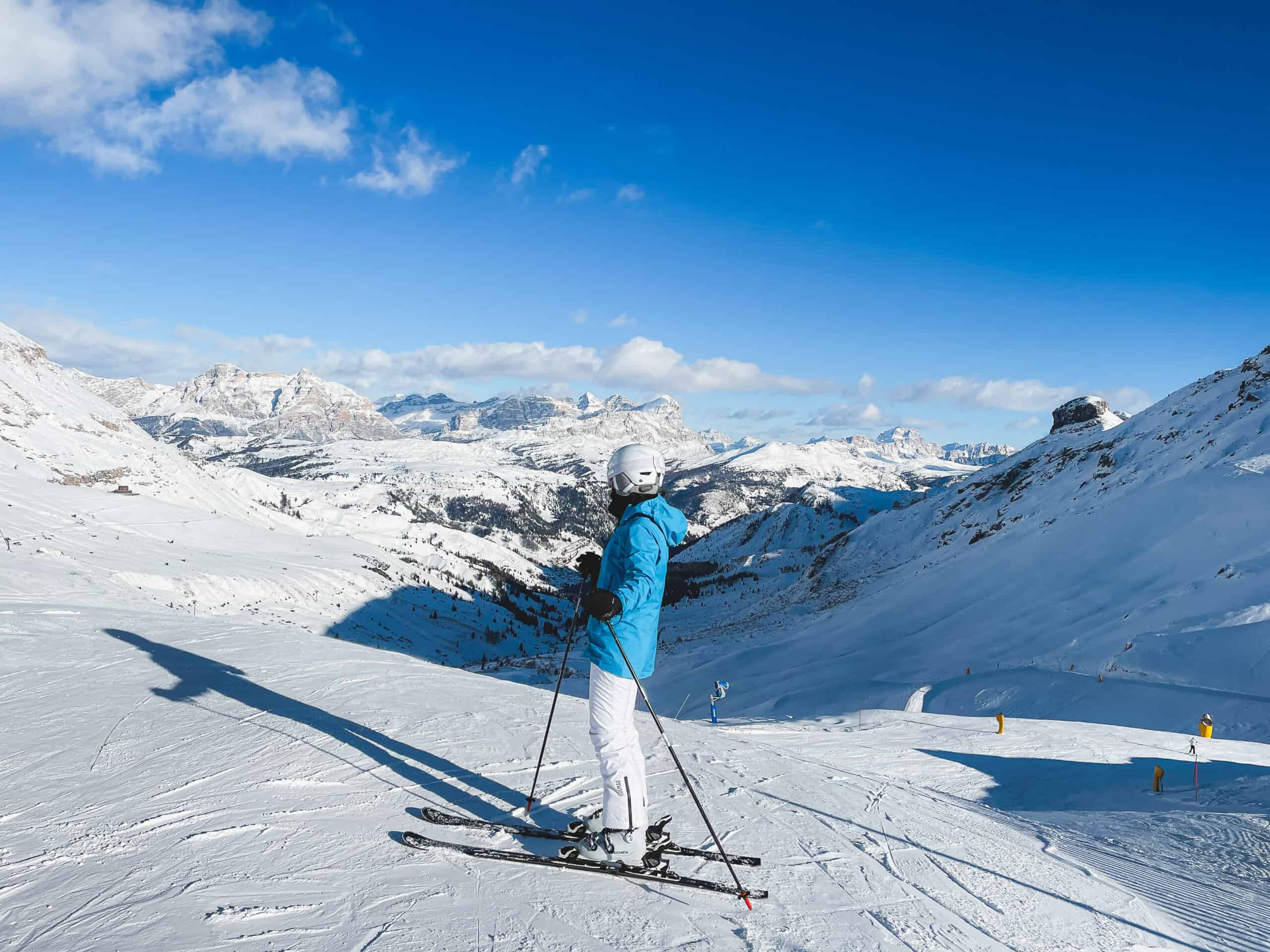 A skier in action on a groomed slope in Alta Badia with the distinct rocky peaks of the Dolomites in the background.