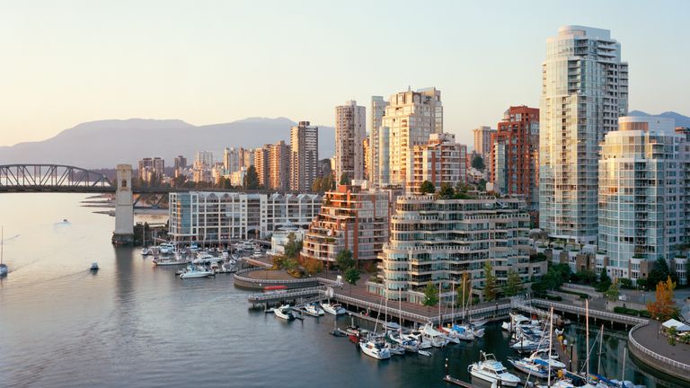People cycling along the paved Vancouver waterfront seawall with the ocean in view.