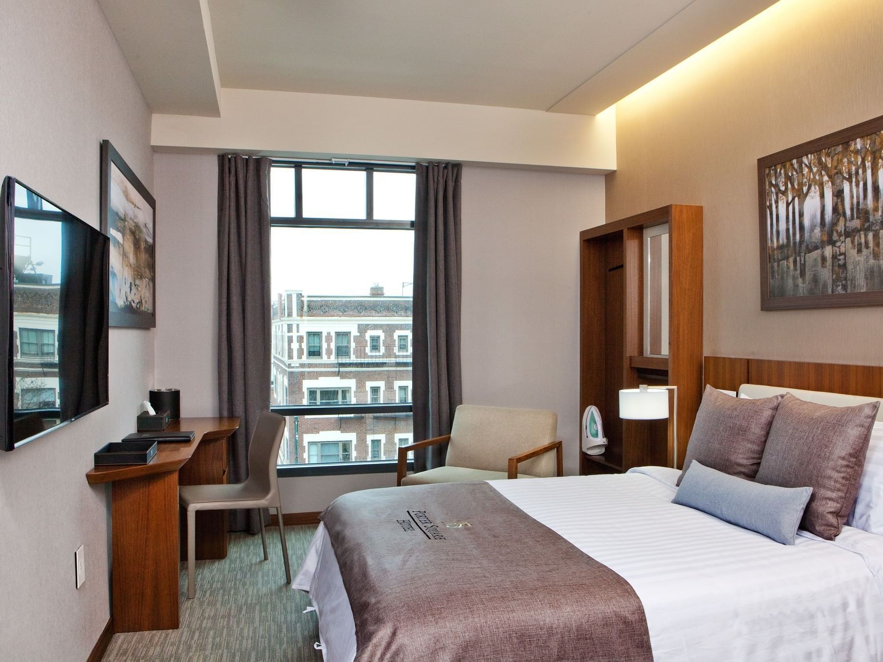 A clean, modern boutique hotel room with a queen bed and minimalist decor.