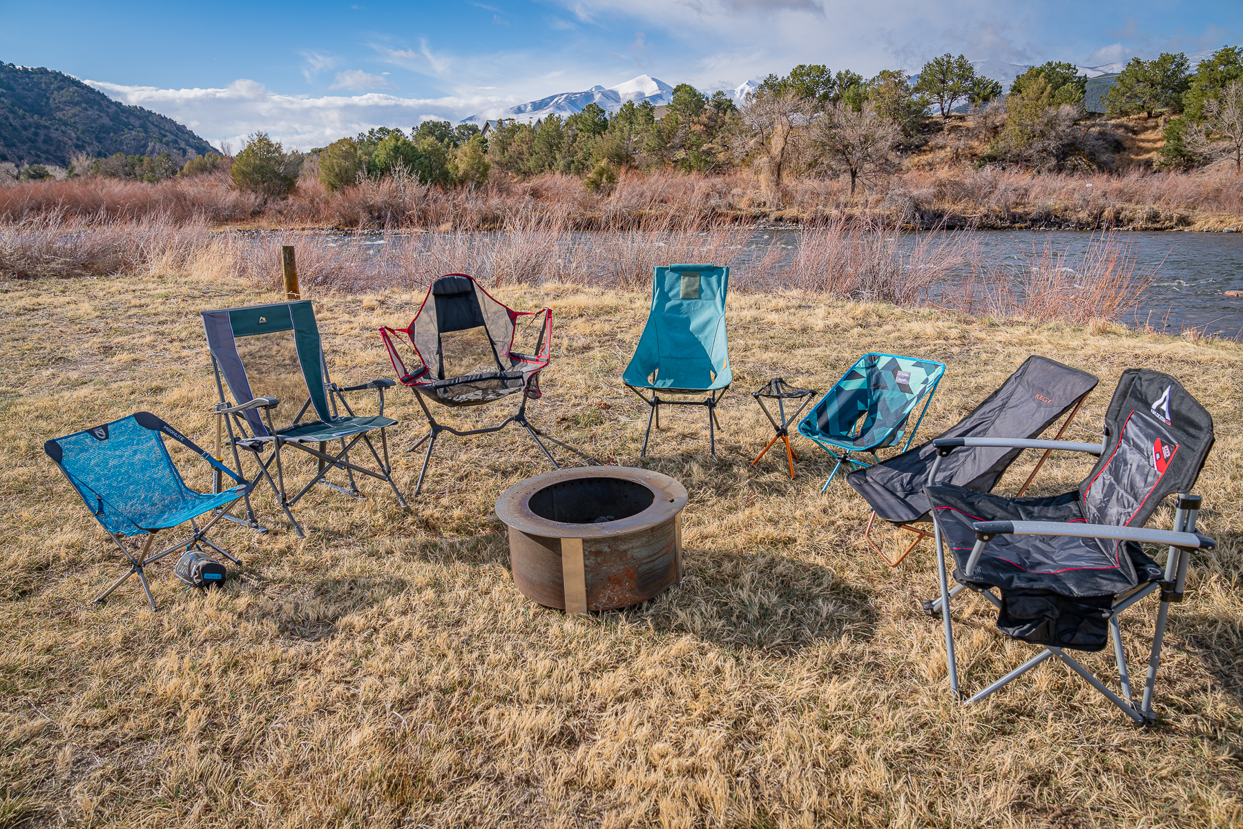 A gear tester assembling a compact camping chair in a green grassy meadow.