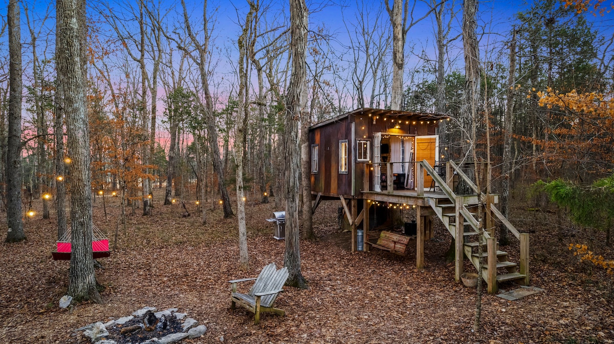 A wooden structure illuminated by warm string lights at twilight.