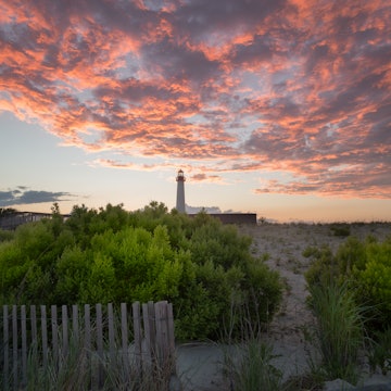 The Cape May Point Lighthouse at sunset with the beach in the foreground.