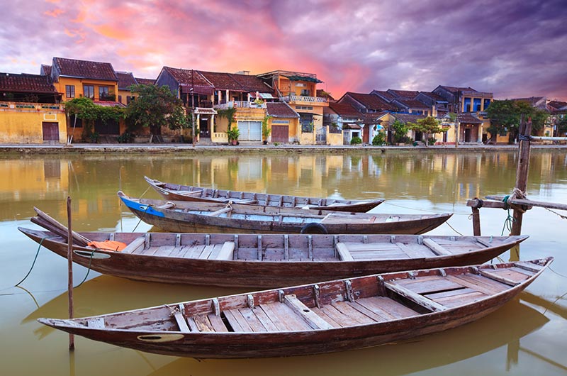 Traditional yellow merchant houses and wooden boats in the historic district of Hoi An.