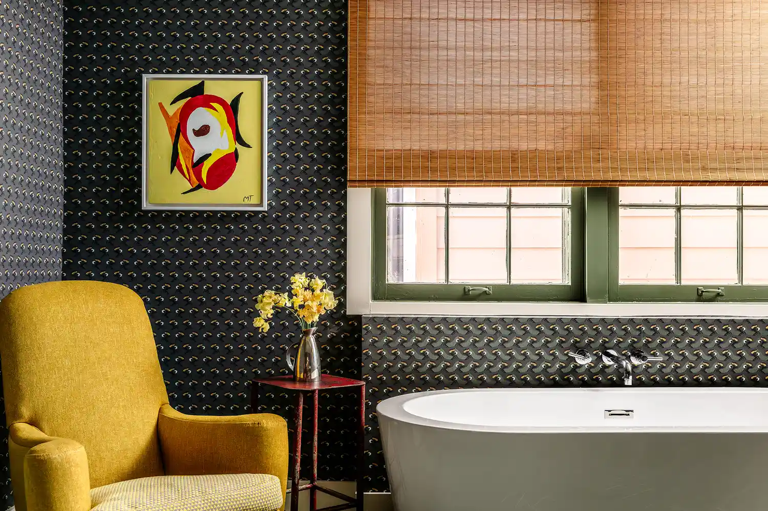 A luxury hotel bathroom with a white soaking tub, yellow accent chair, and floral wallpaper.