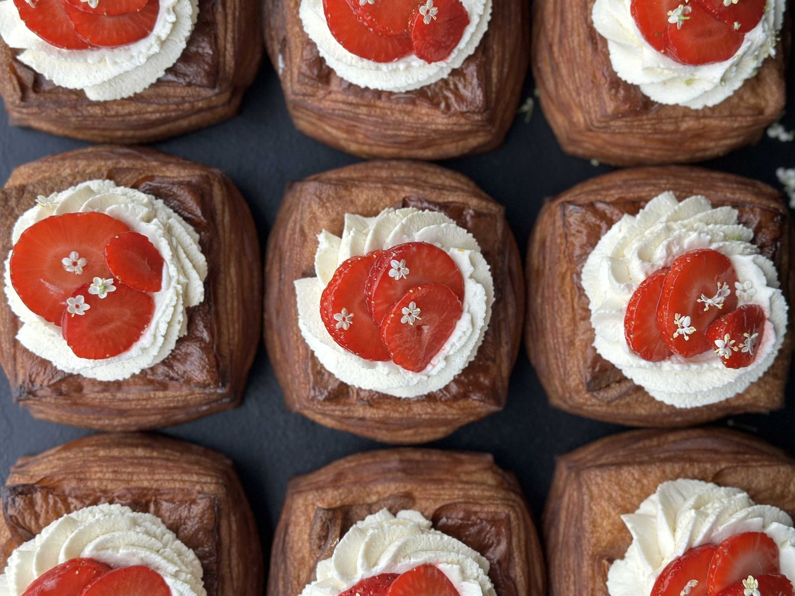 A close-up shot of golden-brown cardamom buns and sugar-dusted pastries in a bakery display.