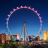 The High Roller observation wheel at The LINQ illuminated in purple and blue against the night sky.