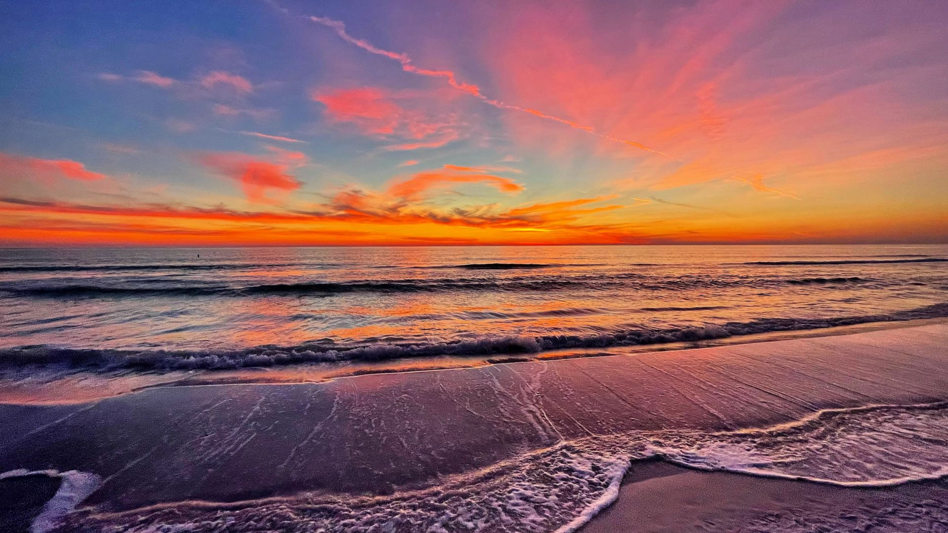 A vibrant pink and orange sunset over the calm ocean waters of Anna Maria Island.