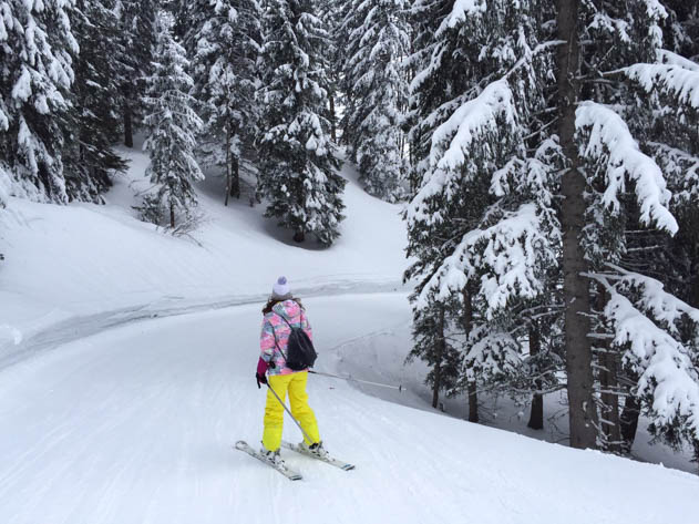 A skier carving through fresh snow at the La Clusaz ski resort with mountains in the background.