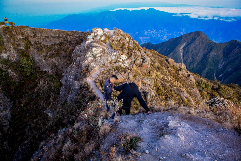 A hiker following a guide up a steep, dusty volcanic incline.