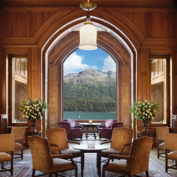 The grand high-ceilinged lobby of Badrutt's Palace known as Le Grand Hall with guests socializing.