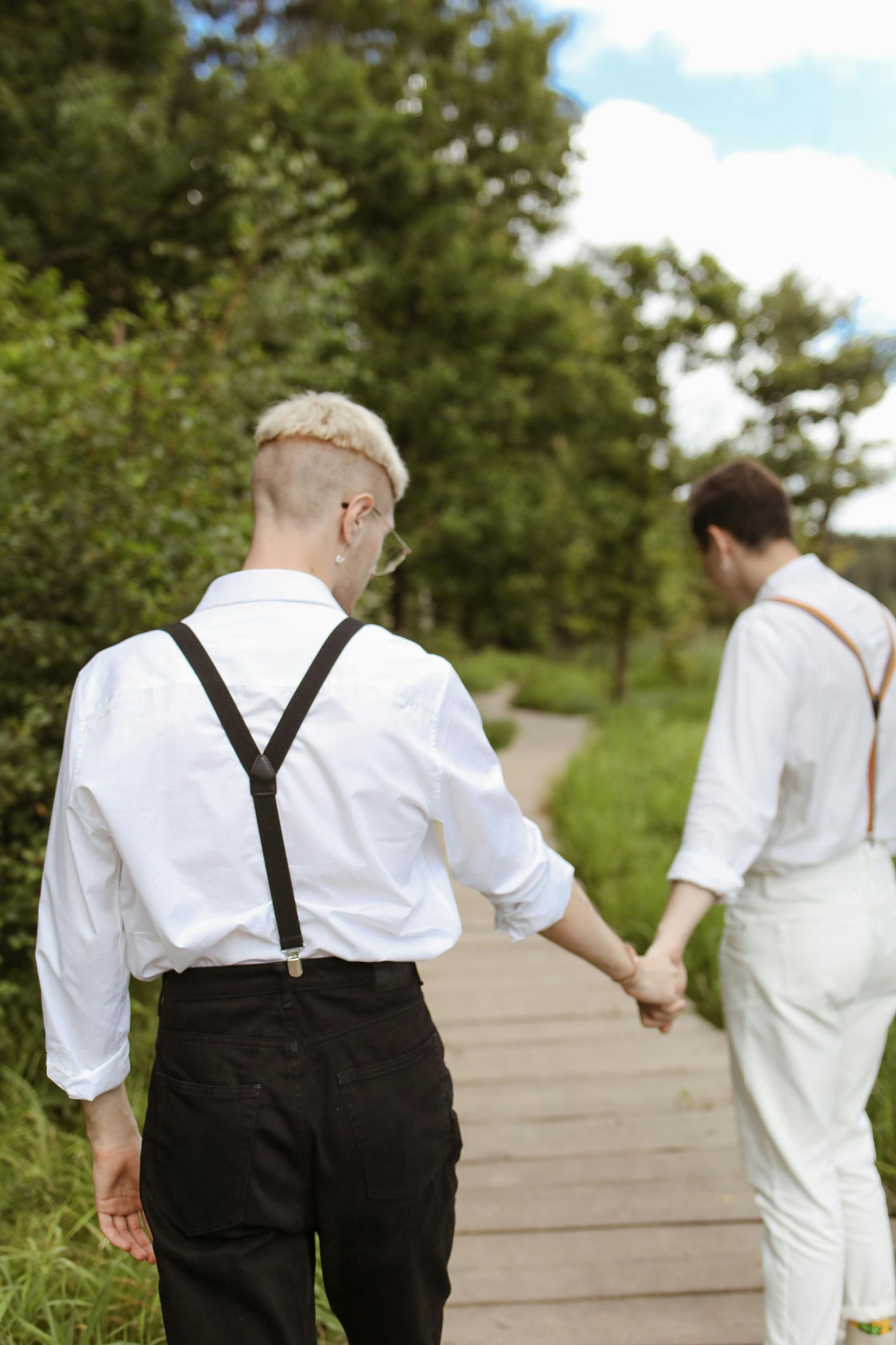 Close-up of a couple's hands joined while walking along a scenic wooden boardwalk.