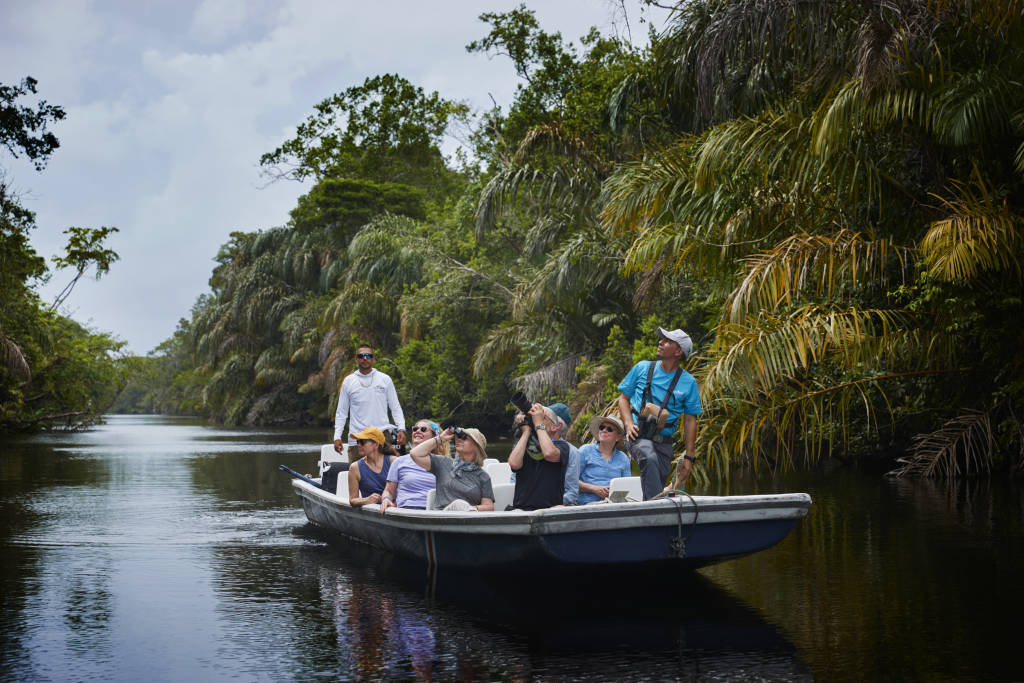 A group of travelers in a boat navigating a lush jungle waterway in Costa Rica.