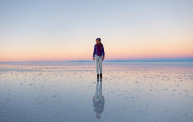 The vast, reflective white surface of the Uyuni Salt Flats in Bolivia under a bright sky.