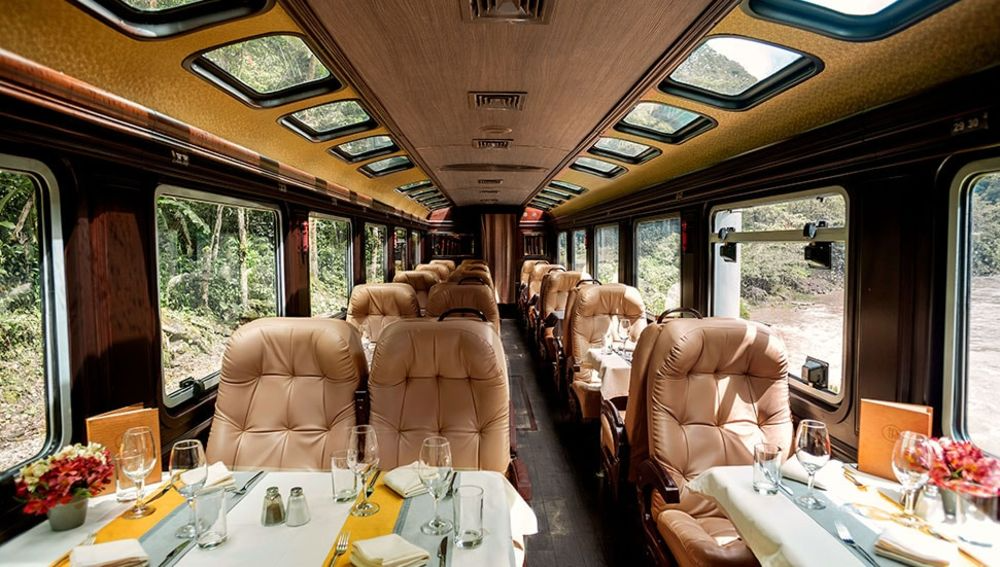 A sophisticated train dining area with white linens and scenic window views.
