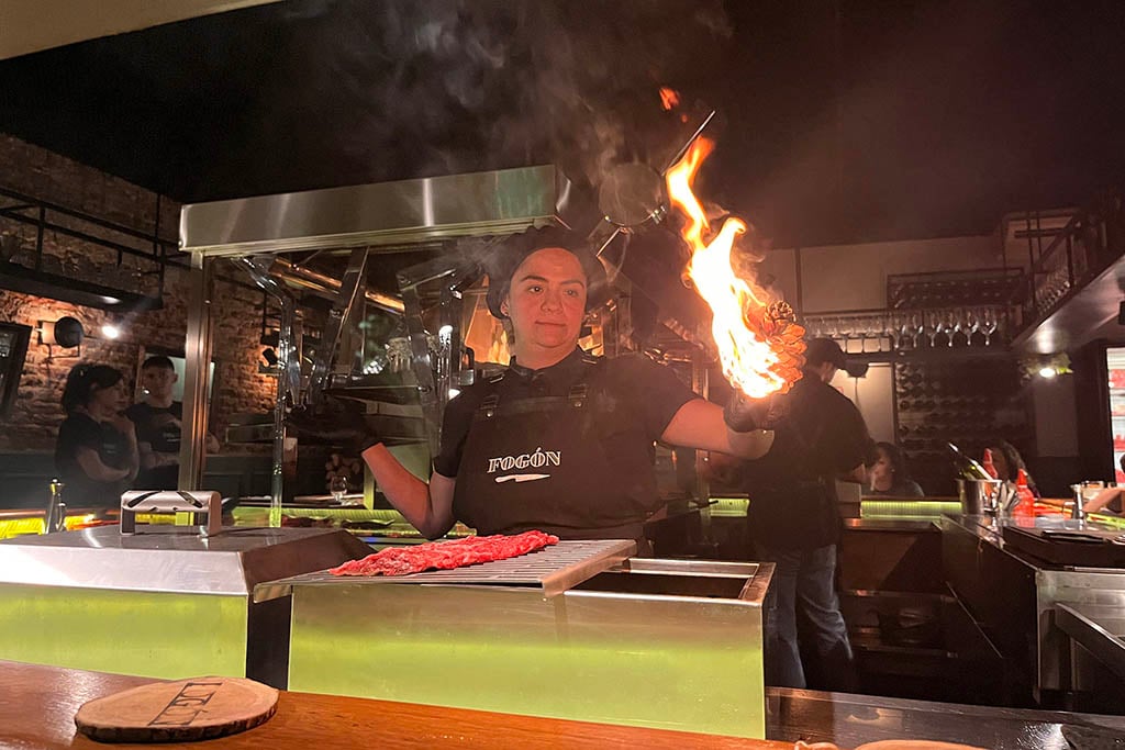 A traditional Argentine asado with various cuts of meat cooking on a large iron grill.