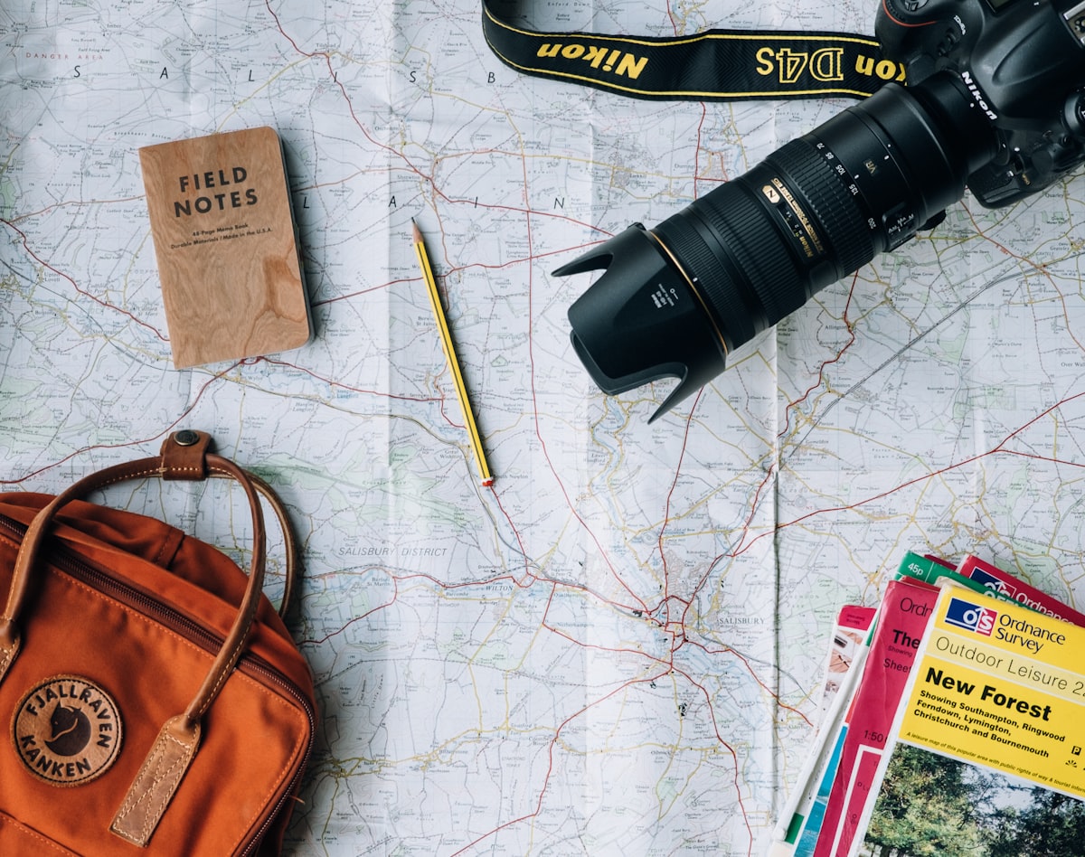 A person looking at a physical map and travel books on a table to plan a route.