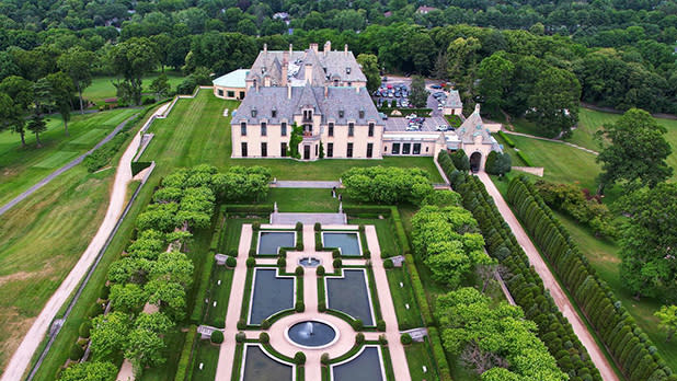 Aerial view of a grand historic castle with manicured gardens and fountains