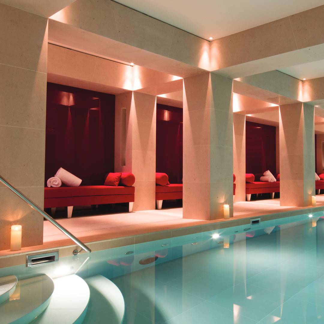 The private indoor swimming pool at La Réserve Paris with columns and soft lighting.