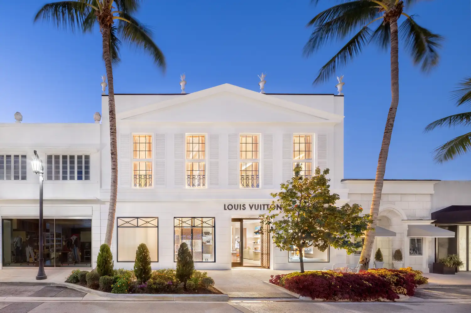 Exterior view of the white stucco Louis Vuitton flagship store in Palm Beach at dusk.