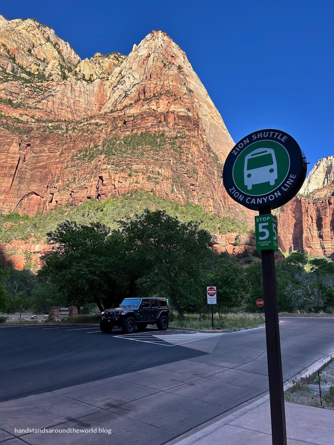 An electric Zion National Park shuttle bus driving through the red rock canyon.