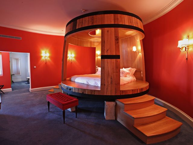 A cozy hotel room interior where the bed is situated inside a large vintage wooden wine barrel.